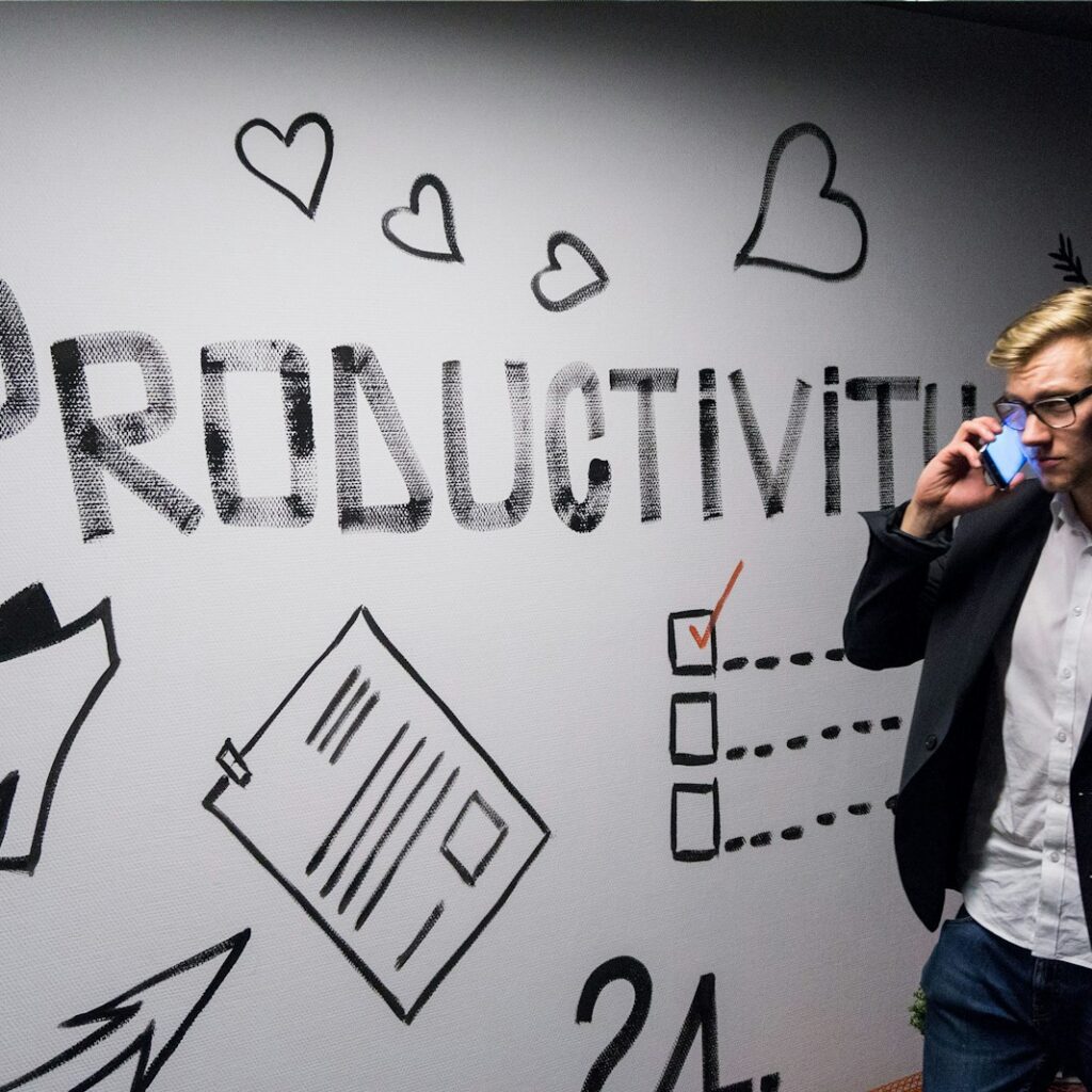 man holding smartphone looking at productivity wall decor